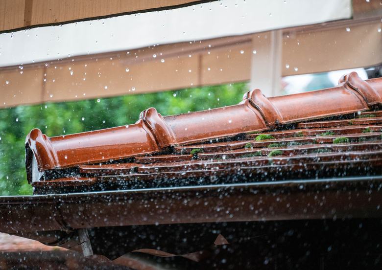 Gouttière et bord de toit en tuiles sous la pluie